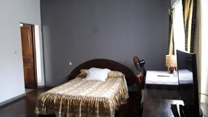 A bedroom with a bed, a desk, and a chair. - Hotel le Colbert (Antsiranana)
