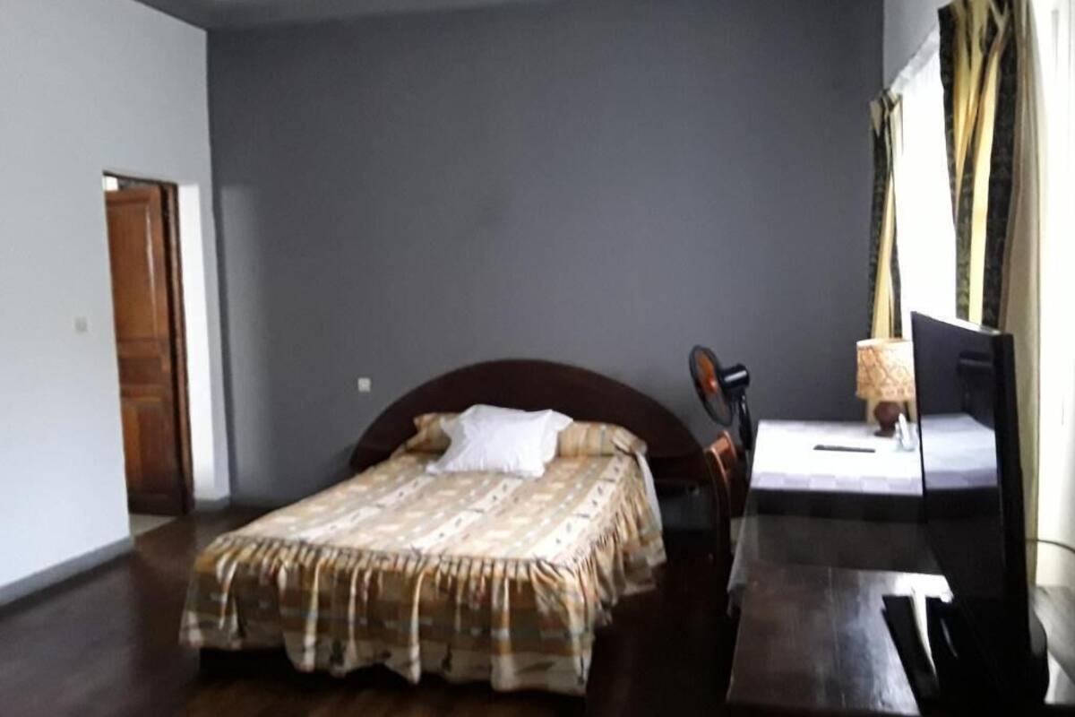 A bedroom with a bed, a desk, and a chair.