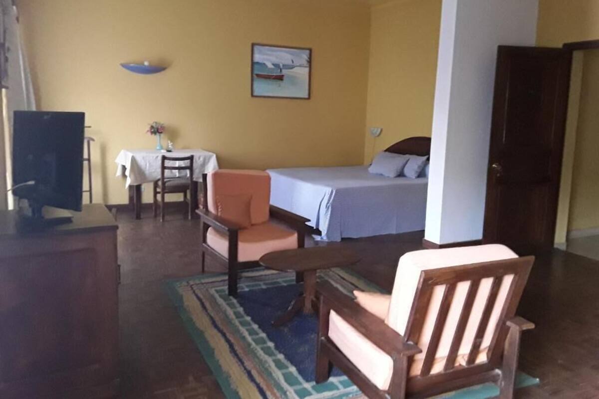 A room with a bed, a desk, a chair, a television, and a painting on the wall.