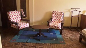 A room with two patterned chairs, a small table, and a hanging coat rack. - Hotel le Colbert (Antsiranana)