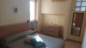 Un dormitorio con una cama, un aparador, una ventana y un espejo.