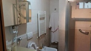 Un baño con lavabo, espejo, toallero, ducha e inodoro bidé.