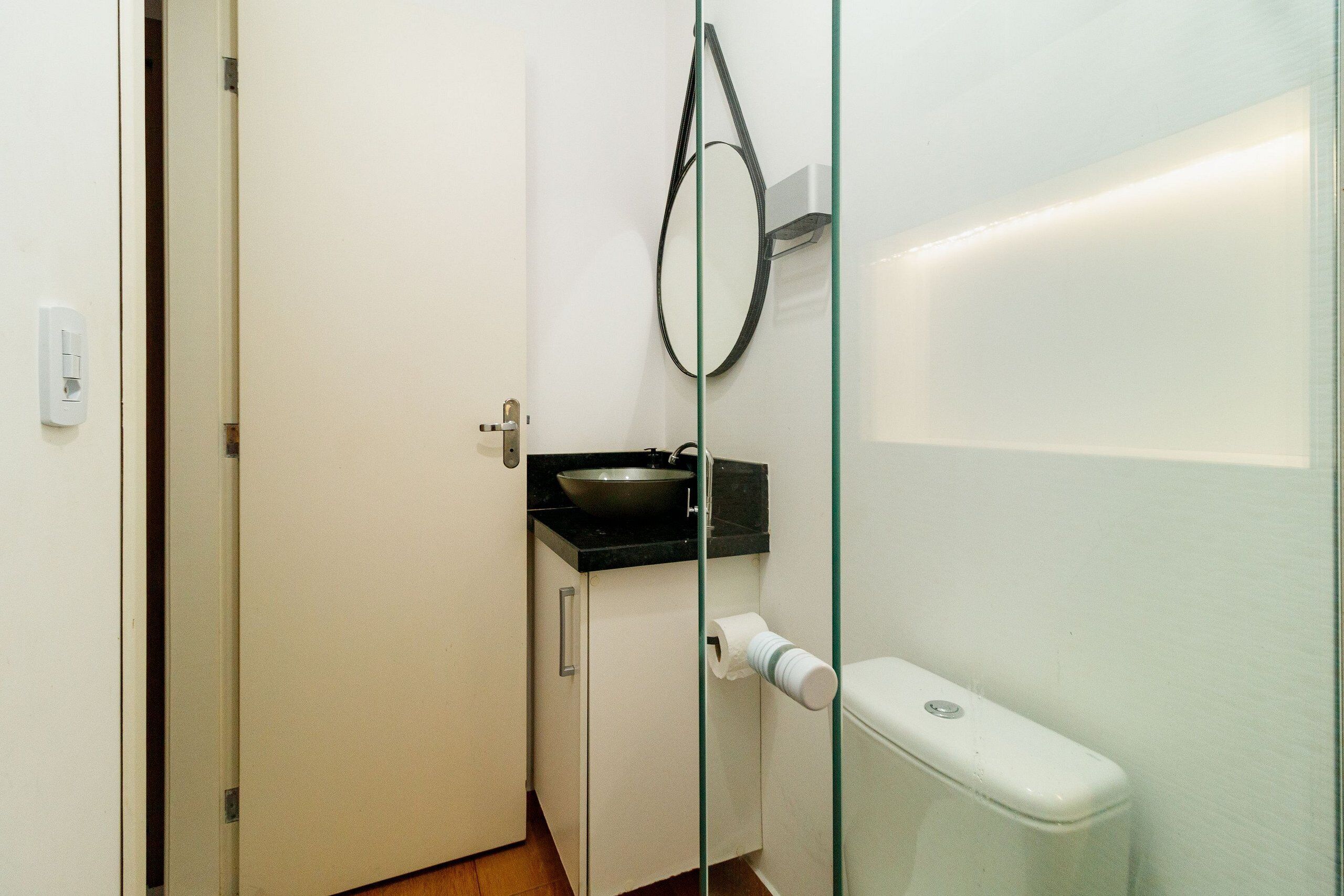 A small bathroom with a toilet, a sink, and a glass partition.