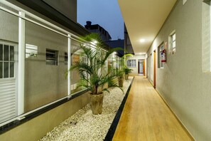 A hallway with a pebble-lined path, potted plants, and a fire extinguisher on the wall. - Studios Tiny House Viva Essa Experiência (São Paulo)