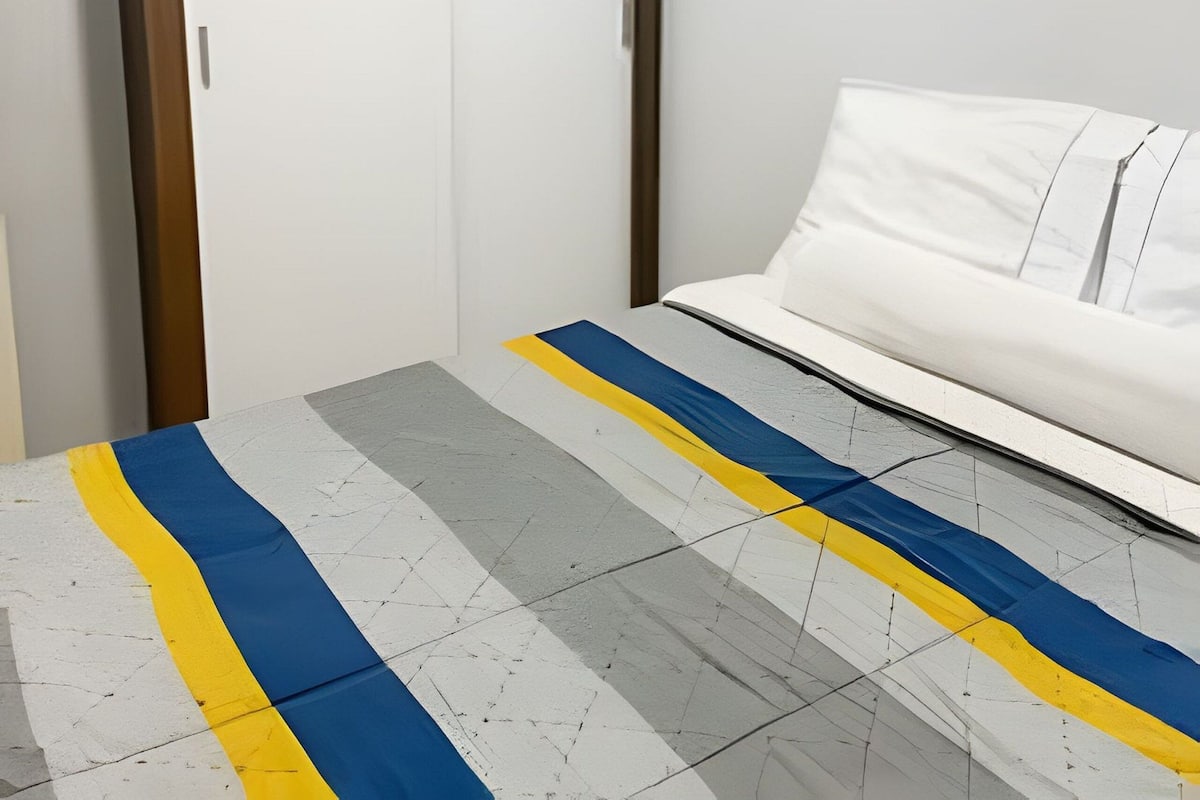 A bedroom with a white sofa, a wooden wardrobe, and a patterned rug.