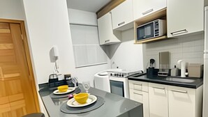 Una cucina moderna con isola centrale, mobili bianchi, un forno a microonde e un piano cottura.