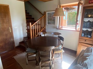 Cozy dining area with a round table and six chairs, featuring a large window with a view of the surrounding greenery.