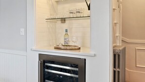 A kitchen with a built-in wine fridge, a glass display shelf with wine glasses, and a wooden floor. - Historic home with modern amenities in the heart of town, walk everywhere! (Marblehead)