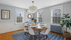 A dining room with a round table set for six, surrounded by white chairs. - Historic home with modern amenities in the heart of town, walk everywhere! (Marblehead)