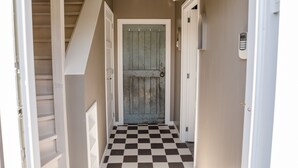 A hallway with a checkered floor, a wooden door, and a staircase. - Sfeervol Vakantiehuisje in het Charmante Yerseke (Yerseke)
