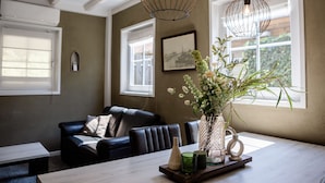 A dining area with a wooden table, chairs, a vase with flowers, and pendant lights. - Sfeervol Vakantiehuisje in het Charmante Yerseke (Yerseke)