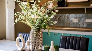 A dining table with a vase of flowers, a candle, and decorative vases. - Sfeervol Vakantiehuisje in het Charmante Yerseke (Yerseke)