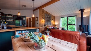 Una mesa de comedor de madera con fruta, una zona de cocina con estufa y un espacio de descanso con sofá de cuero.