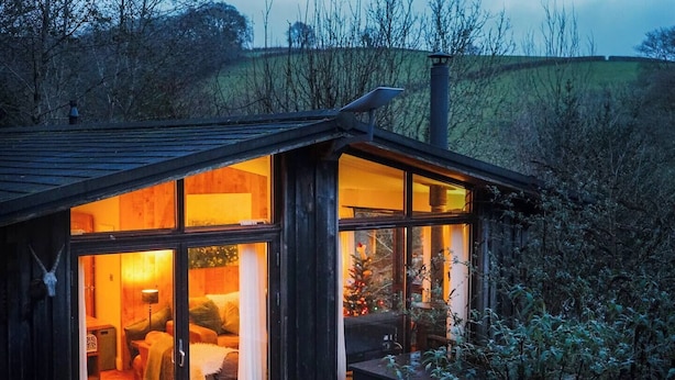 Una cabaña acogedora con un interior cálido, ventanas amplias y vistas del paisaje circundante.