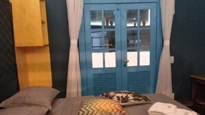 A bedroom with a bed, pillows, a wardrobe, and a window with curtains. - Residencial Casa Flor Atelier Botânico, Ponta Negra (Natal)