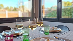 A dining table set with wine glasses, plates, and cutlery, with a view of greenery outside. - Morera Blanca (Canet de Fals)