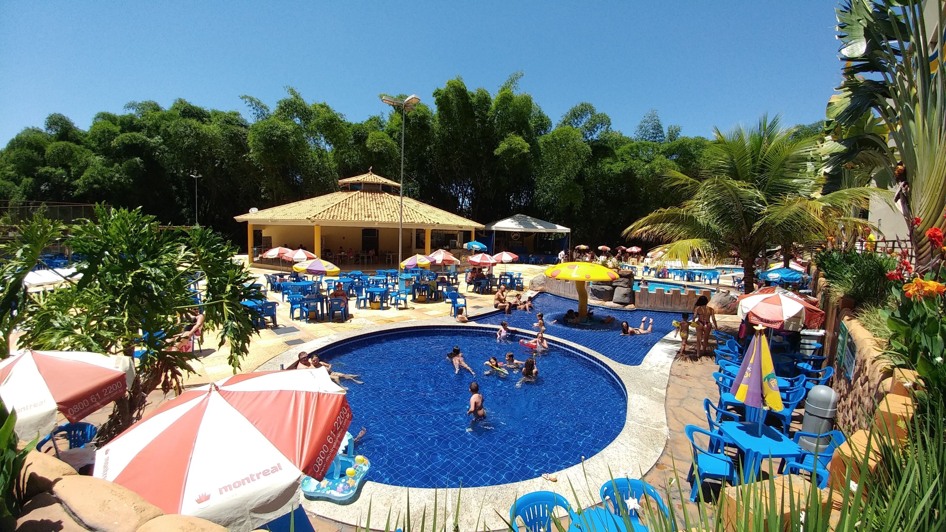 Ein Schwimmbeckenbereich mit Liegestühlen, Sonnenschirmen und einer überdachten Sitzgelegenheit.