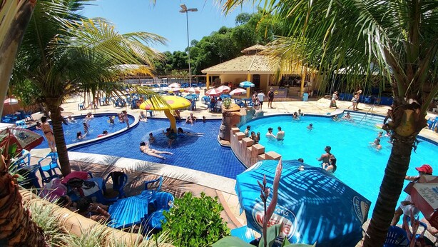 A pool area with multiple swimming pools, lounge chairs, and umbrellas. - Golden Dolphin 01 Quarto - Caldas Novas -GO (Caldas Novas)
