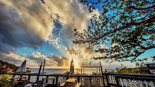 A wooden deck with lounge chairs, a small table, and a gazebo overlooking the sea. - Sunny bay hotel (Liuqiu)