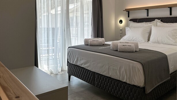 Habitació d'hotel amb un llit, una taula de nit, una finestra amb cortines, un aparell d'aire condicionat i una làmpada penjada a la paret.