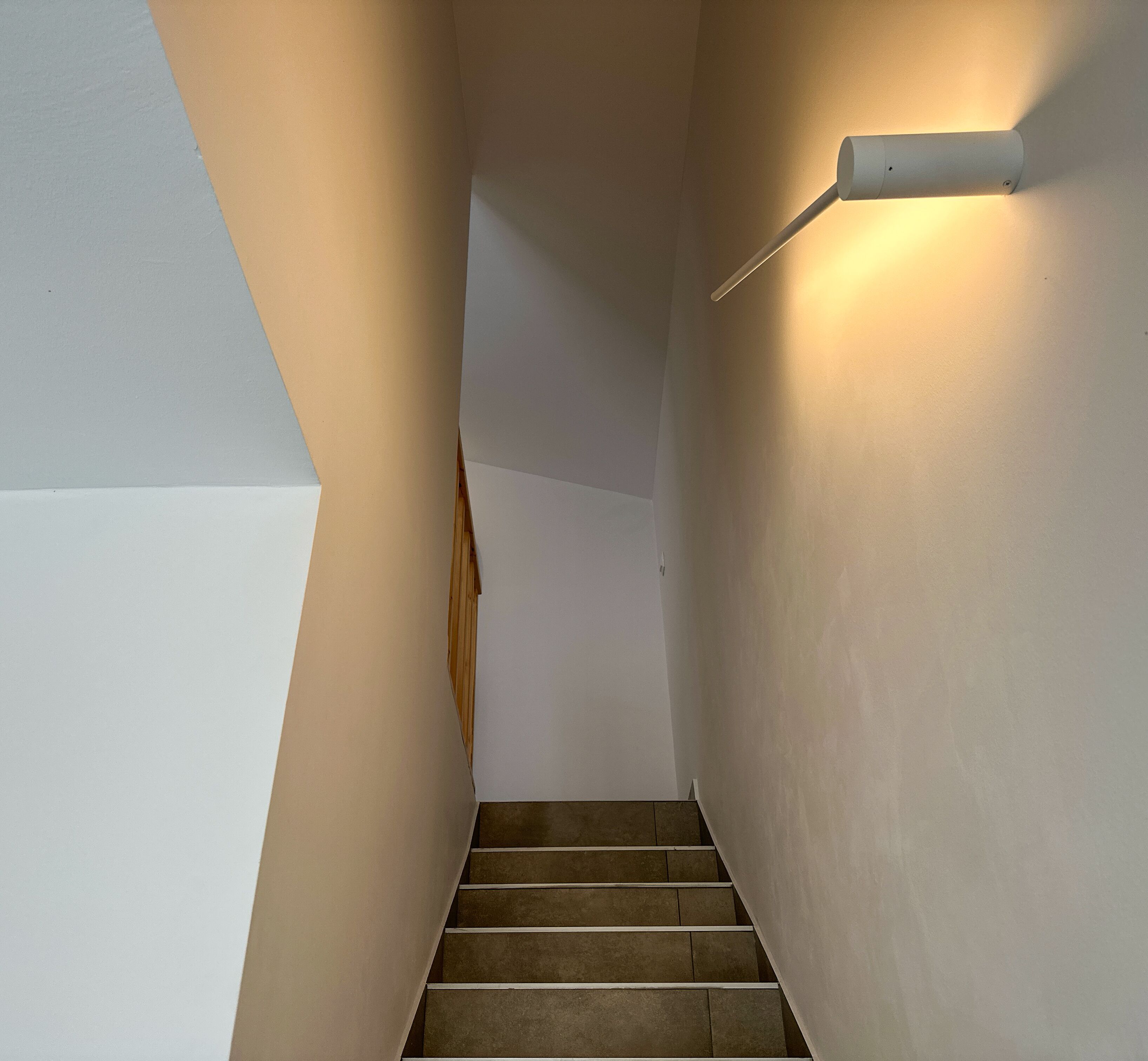 A staircase with a light fixture on the wall.