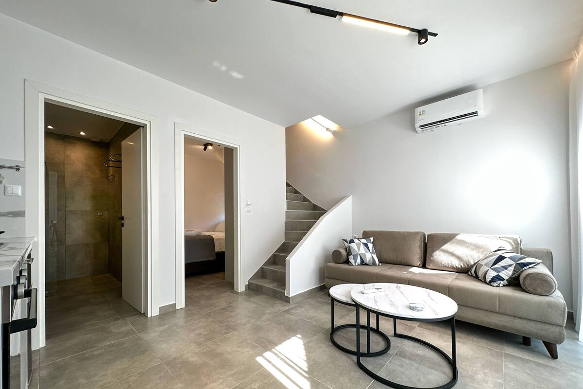 Una sala de estar moderna con sofá, mesa de centro y una escalera.