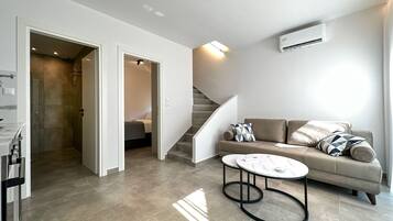 A modern living room with a sofa, coffee table, and a staircase.