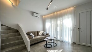 Un saló modern amb una escala, un sof à, una taula de centre i una porta.