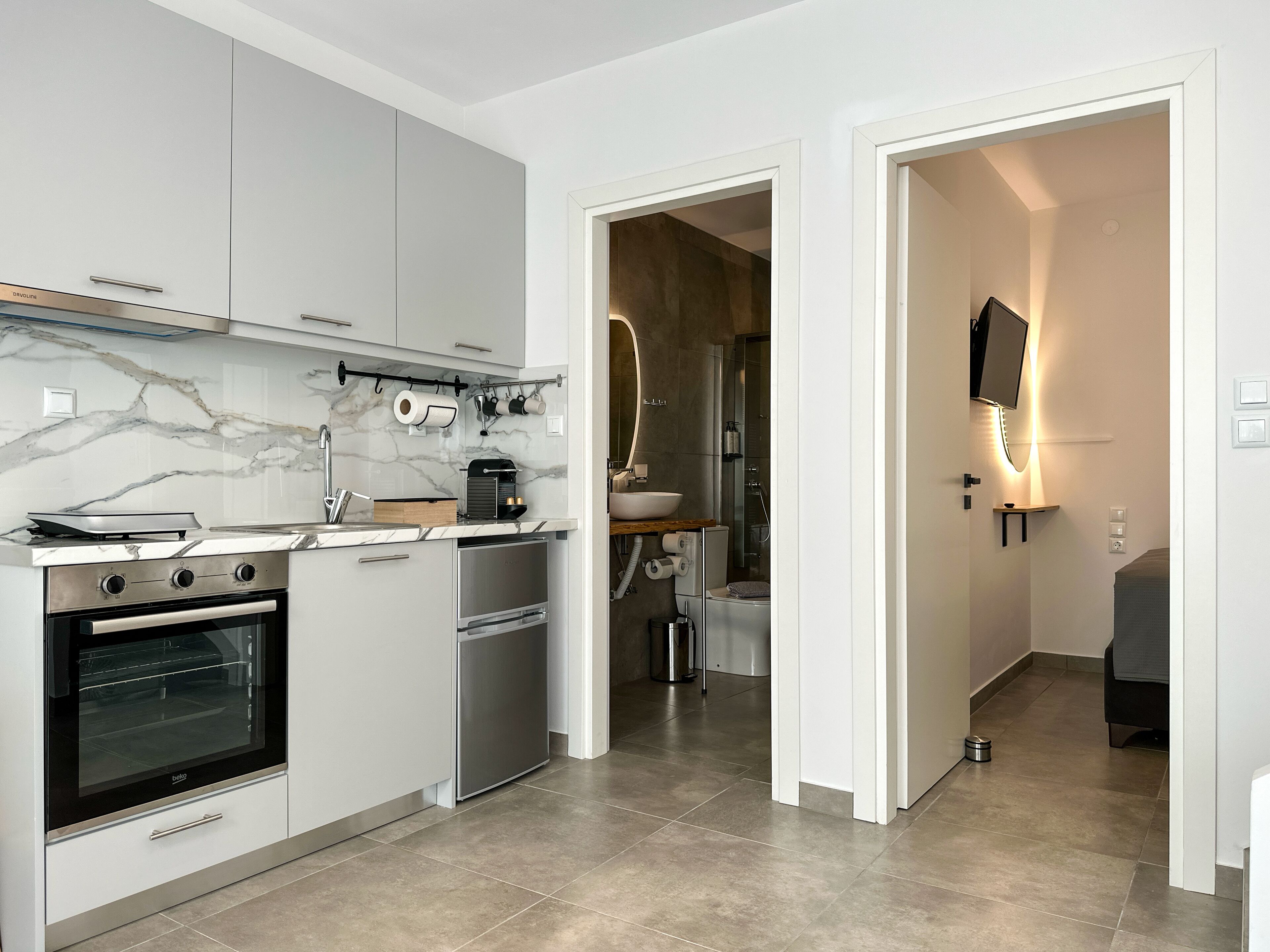 Een moderne keuken met witte kasten, een inbouwoven en een koffieapparaat.