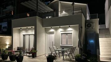 Una casa moderna de dos pisos con balcón, zona de estar al aire libre y una escalera que conduce al piso superior.