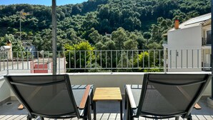 Una terrassa amb dues cadires i una taula, amb vista a un turó forestal.