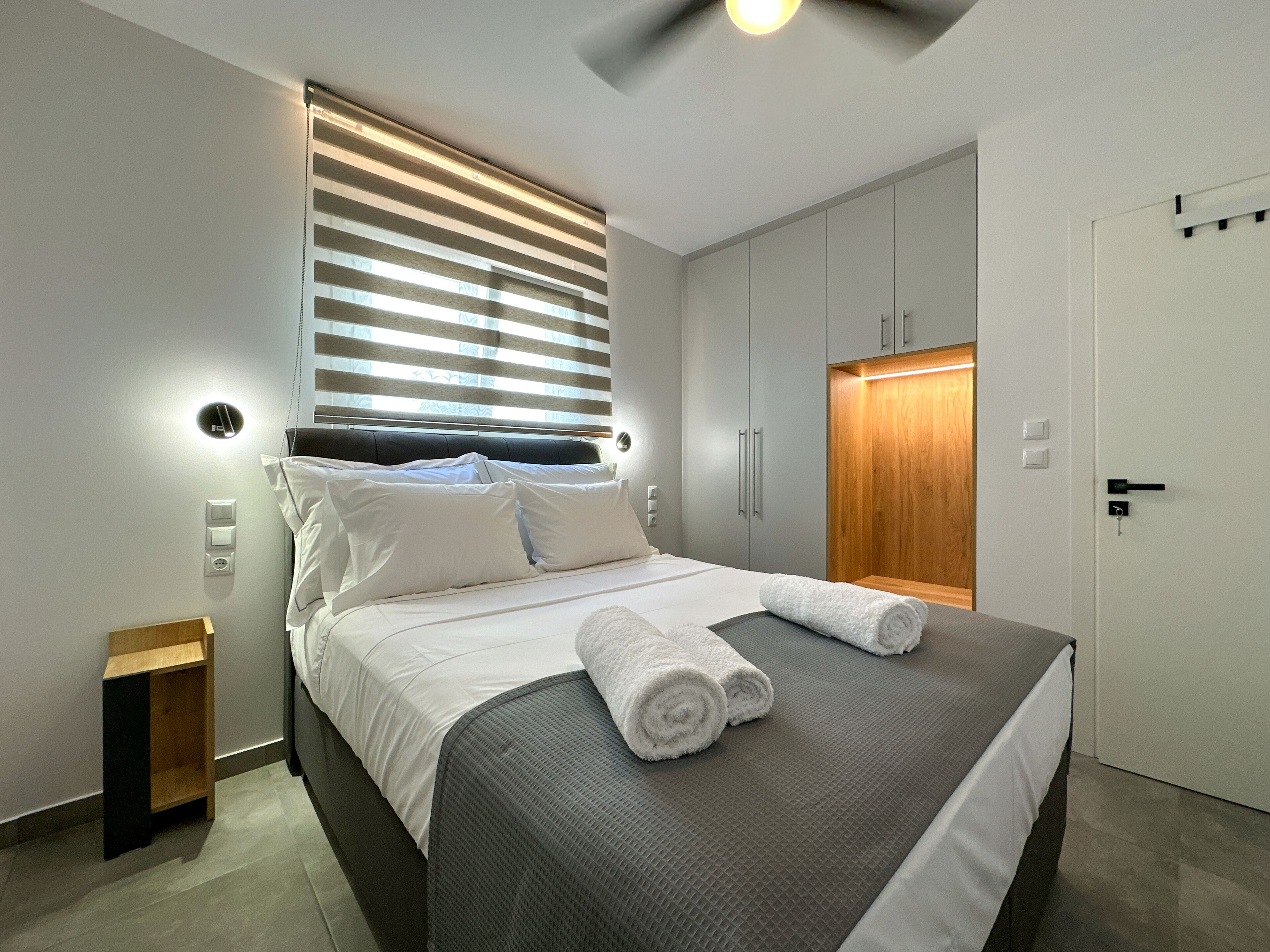 A modern bedroom with a bed, bedside tables, and a wardrobe.