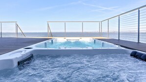 Un jacuzzi en una terraza con vistas al mar y un puente a lo lejos.