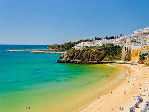 Un pueblo costero con una playa arenosa, aguas azules cristalinas y edificios blancos.