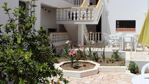 A multi-level courtyard with white railings, outdoor seating, and a garden area with various plants and flowers. - Albufeira 2 - Beach & Old Town (Albufeira)