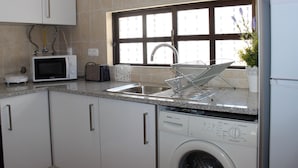 A modern kitchen with a built-in dishwasher, a microwave, and a window with a view of the outside. - Albufeira 2 - Beach & Old Town (Albufeira)