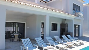 A poolside area with lounge chairs and a dining table. - Villa Goncinha - Private Pool & BBQ (Loulé)