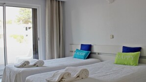 Et hotelværelse med to senge, hver med pude, en stol og udsigt ud