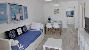 A compact living space with a sofa, dining table, chairs, and a TV.