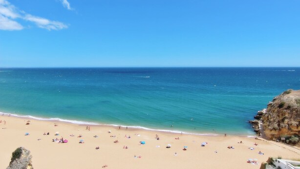 A beach with clear blue water, sandy shore, and rocky cliffs. - Casa dos Tios - Sea View, Beach & Old Town Center (Albufeira)