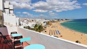 A balcony with outdoor seating overlooking a beach and cityscape. - Casa dos Tios - Sea View, Beach & Old Town Center (Albufeira)