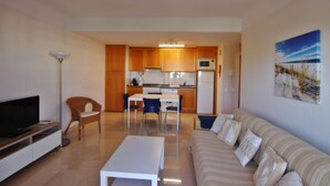 A living room with a sofa, a TV, and a dining area with chairs and a table.