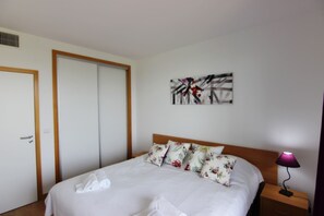 Een hotelkamer met een bed, een nachtkastje met een lamp, een deur en een muur met een schilderij.