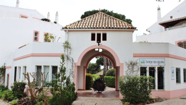 A building with a white facade, a tiled roof, and an archway entrance. - Solar do Golfe - Pools & Old Village (Vilamoura)