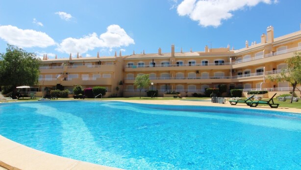 Un hôtel doté d’une piscine, de nombreux balcons et offrant une vue sur un ciel d’un bleu éclatant.