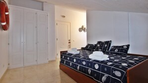 Une chambre à coucher avec un lit, une armoire blanche et un gilet de sauvetage accroché au mur.