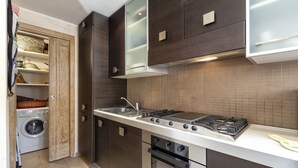 Una cocina compacta con lavadora integrada, estufa y microondas.