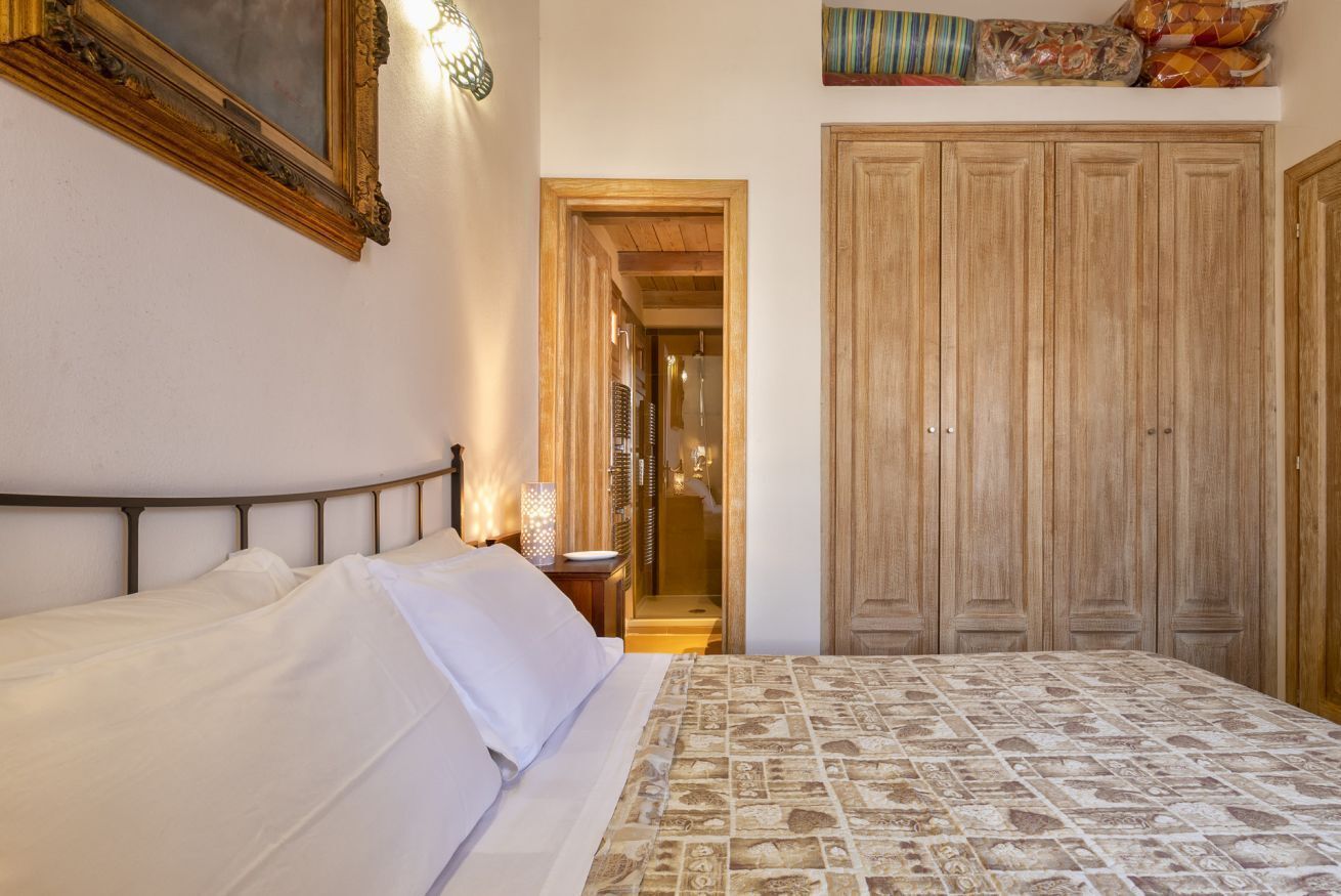 A bedroom with a bed, a wooden wardrobe, and a framed picture on the wall.