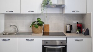 A modern kitchen with white cabinets, a stainless steel sink, a built-in oven, and a coffee maker. - Casa Libeccio. Apartment in the center with A/C and free wi-fi. (Alghero)