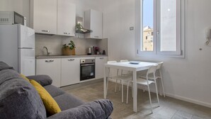 Eine kleine Küche mit weißen Schränken, einem eingebauten Backofen und einem Fenster für natürliches Licht.